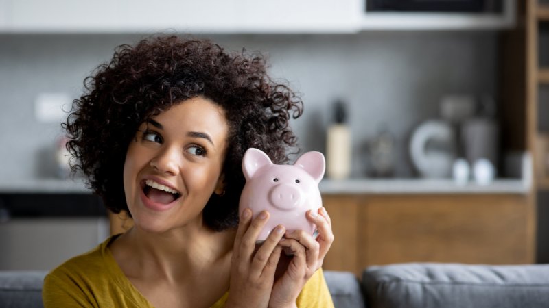 lachende junge Frau mit Sparschwein