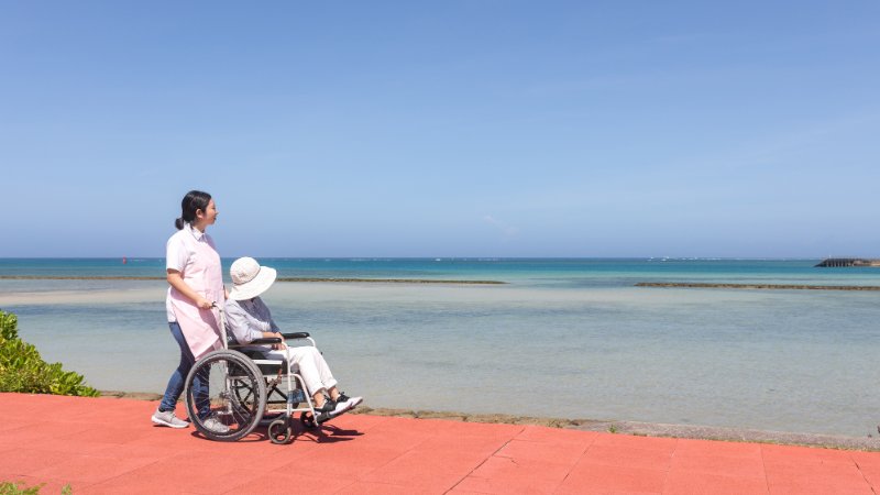 Seniorin im Rollstuhl an der Strandpromenade