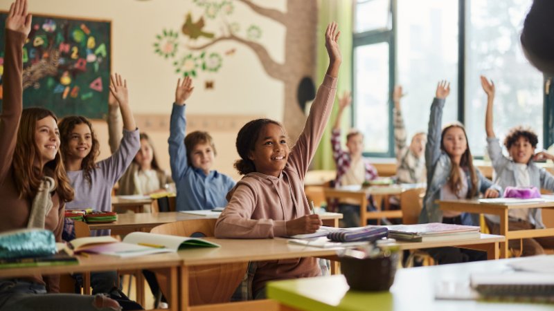 Schulklasse: Alle Kinder heben die Hand
