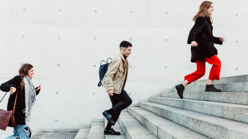 3 junge Leute laufen eine Treppe hoch