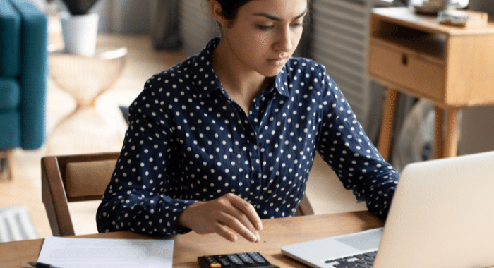 Frau vor Laptop und Taschenrechner
