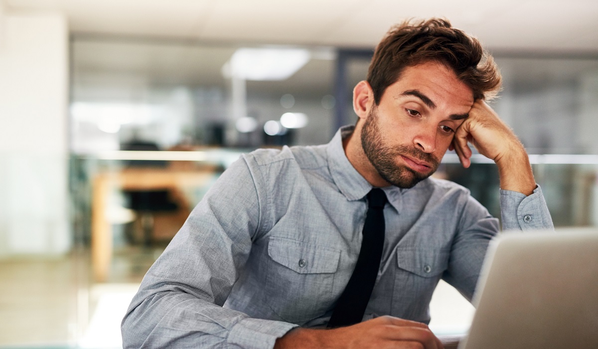 Mann sitzt mit Boreout vor dem Laptop