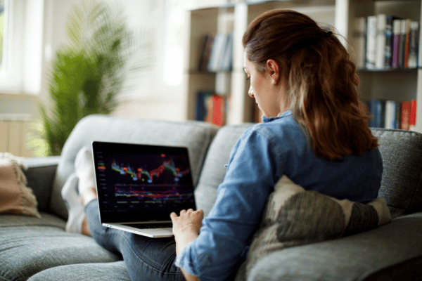 Frau sitzt auf der Couch und informiert sich am Laptop über betriebliche Altersvorsorge mit ETF