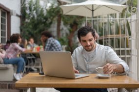 Mann im Café informiert sich am Laptop zu Rentenversicherung