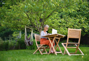 Seniorin mit Laptop am Gartentisch