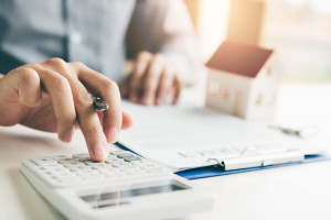 Erbschaftssteuer und Immobilien: Mann kalkuliert Erbschaftssteuer mit einem Taschenrechner