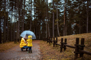 Mutter mit Kind unter Schirm im Wald